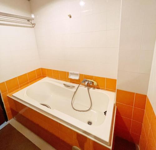 Ban Khlong ThewaTHE POPULAR PLACE的浴室铺有橙色和白色瓷砖,配有浴缸。