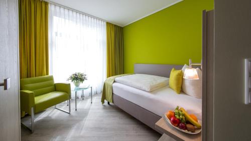 诺德奈Michels Inselhotel Vier Jahreszeiten的一间卧室设有绿色的墙壁和一张带一碗水果的床。