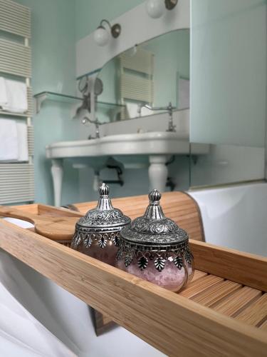 富热尔Mercier de Montigny - Les Chambres du Beffroi - SPA et Massage的浴室设有水槽和架子上的两个花瓶