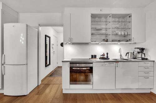 奥斯陆Tjuvholmen II, As Home的厨房配有白色橱柜和冰箱。