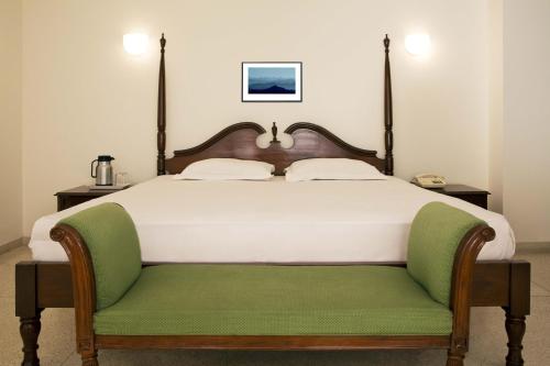 哈里瓦阿尔帕纳酒店的一间卧室配有一张大床和绿色长凳