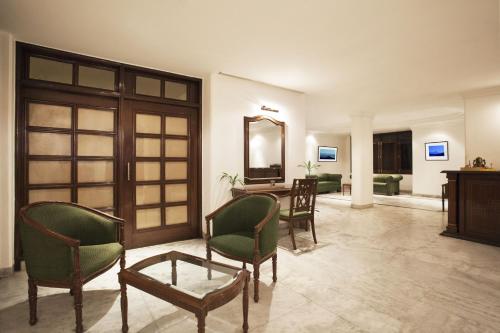 哈里瓦阿尔帕纳酒店的客厅配有椅子、桌子和镜子