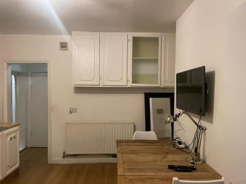 伦敦Balham, South London Spacious Guest House 4的厨房配有白色橱柜和书桌及电视