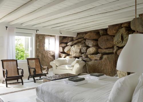 帕瑞加Paradise Estate Community的一间卧室设有石墙、一张床和椅子