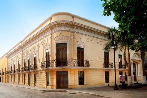 梅里达Mansión Mérida Boutique Hotel - Restaurant的一座大型黄色建筑,位于街道上,设有阳台