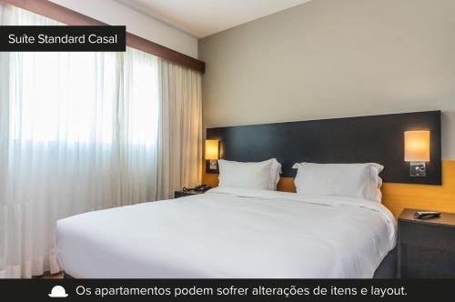 圣保罗Paraíso Suítes by Charlie的卧室设有一张白色大床和一扇窗户。