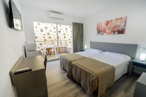 贝尼多姆Hostal Anna Benidorm的酒店客房配有一张床、一张书桌和一台电视。