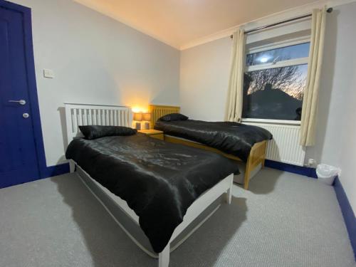 金斯林Harewood Lodge - Single and Double Rooms Self Serve Apartment的一间卧室设有两张床和窗户。