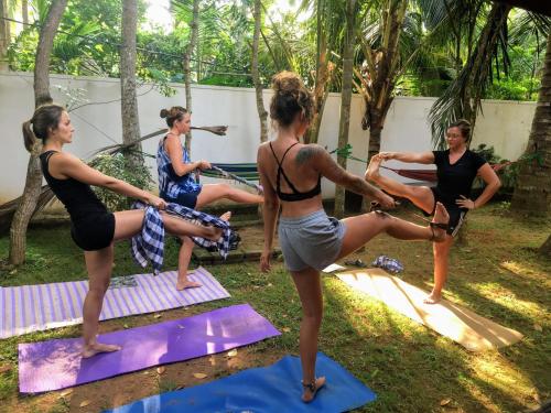 乌纳瓦图纳Hostel Singha Lounge的一群在院子里做瑜伽的女人