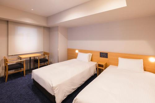 札幌Sotetsu Fresa Inn Sapporo-Susukino的酒店客房配有两张床和一张书桌