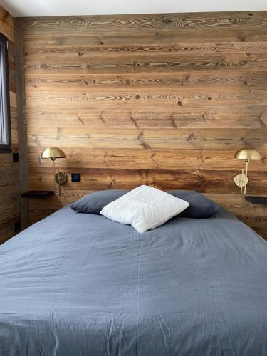土绪尔Le Marlou的一间卧室配有一张带木墙和两盏灯的床。