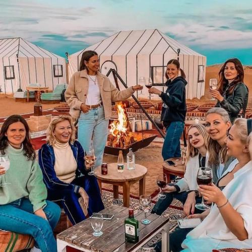 梅尔祖卡Desert Lover's Luxury Camp的一群妇女坐在帐篷前的火堆旁