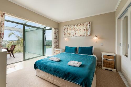 派西亚Swallows Nest - Paihia Holiday Home的一间卧室设有蓝色的床和一个阳台