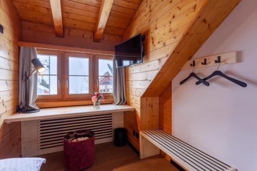 安德马特Sonne Andermatt Swiss Quality Hotel的小木屋内的房间,设有长凳和窗户