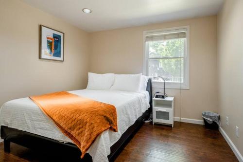 萨克拉门托*2bdr Victorian Home away from Home - *Central Loc的一间卧室配有一张带橙色毯子和窗户的床。