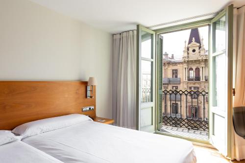 巴塞罗那欧尼斯兰布拉酒店的一间卧室设有一张床和一个大窗户
