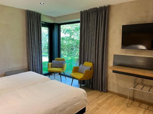 拉罗什-阿登克莱尔方丹国际之家酒店的酒店客房配有一张床、两把椅子和一个壁炉