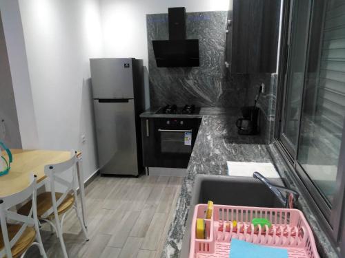 乌姆苏克Résidence Inès Djerba Appartement de Luxe的厨房配有水槽、桌子和冰箱