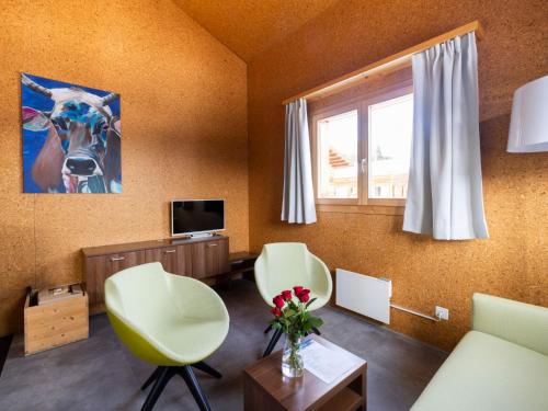 UrmeinHoliday Home Komfort Aclas Maiensäss Resort-1 by Interhome的客厅配有两把椅子和电视
