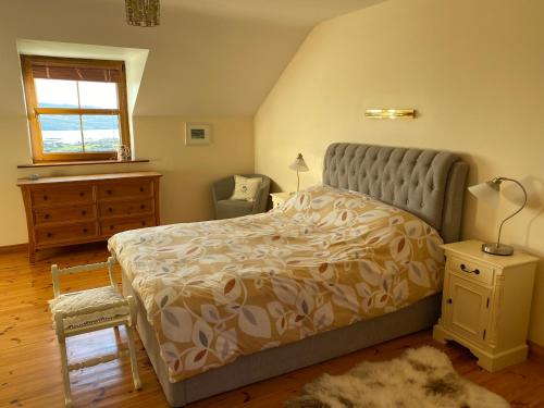 KnocknaudStunning hideaway on the Wild Atlantic Way的卧室配有床、椅子和窗户。