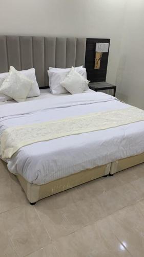 利雅德Reef 18 by Al Azmy的一张配有白色床单和枕头的大床