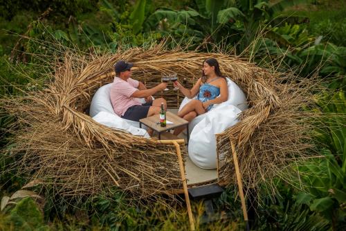 金巴亚Eco Hotel La Colina Mirador的坐在稻草圈里的男人和女人,喝着饮料