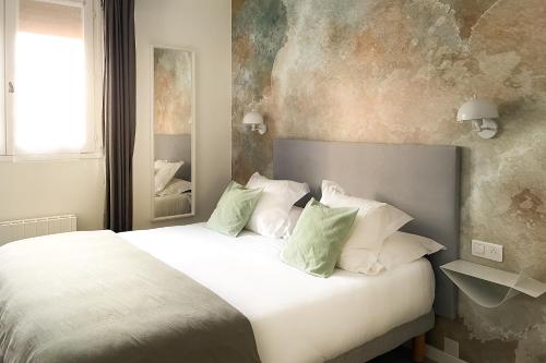 阿维尼翁马南酒店的卧室配有带绿色枕头的大型白色床