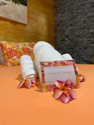 普纳奥亚TAMANU LODGE的一间酒店客房,床上摆放着毛巾和鲜花