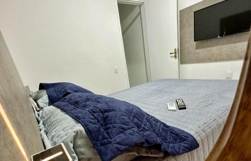 福塔莱萨Fortal Flat的一张带蓝色棉被和遥控器的床