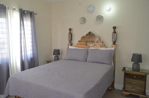 卢西Jamaica Tranquility的一间卧室配有一张床,墙上挂有两盏灯和钟。