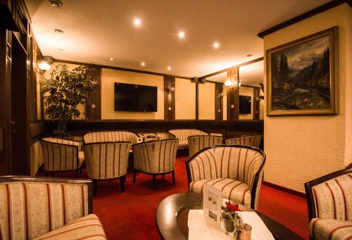 皮耶什佳尼GRAND HOTEL SERGIJO RESIDENCE superior Adult only luxury boutique hotel的一间带椅子和桌子的餐厅以及一台电视