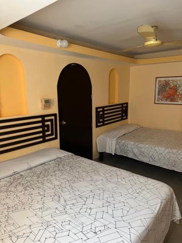 阿卡普尔科Hotel magallanes con cocineta 100 Metros de playa的一间卧室设有两张床和一扇黑色的门