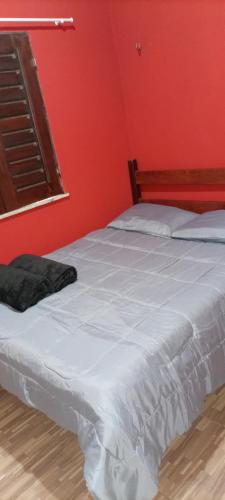 瓜拉米兰加Casa Friozinho da serra的卧室配有白色的床铺和红色的墙壁