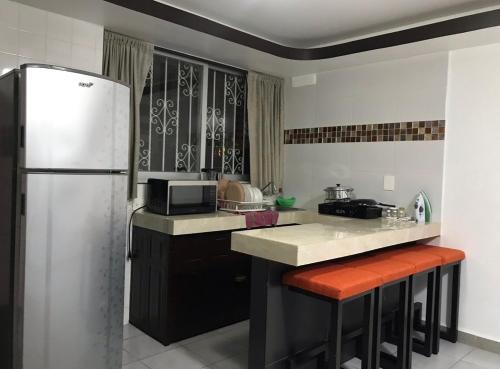 阿卡普尔科Hotel magallanes con cocineta 100 Metros de playa的厨房配有冰箱和带凳子的台面