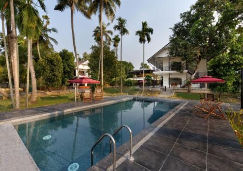 科钦Lhasa Ayurveda and Wellness Resort - A BluSalzz Collection, Kochi, Kerala的一座棕榈树游泳池和一座房子