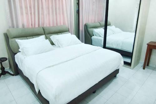 万挠Embun Bayu Musliim homestay的卧室配有一张白色大床和镜子