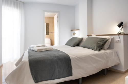 贝尼多姆CALMA Apartments的卧室配有带灰色枕头的大型白色床