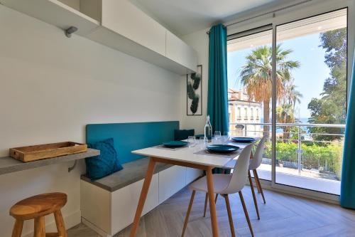 芒通Le Vallaya Suites & Spa的一间带桌椅和大窗户的用餐室