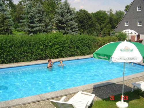 DorfchemnitzGaststätte & Pension Alte Mühle的2人使用带遮阳伞的游泳池