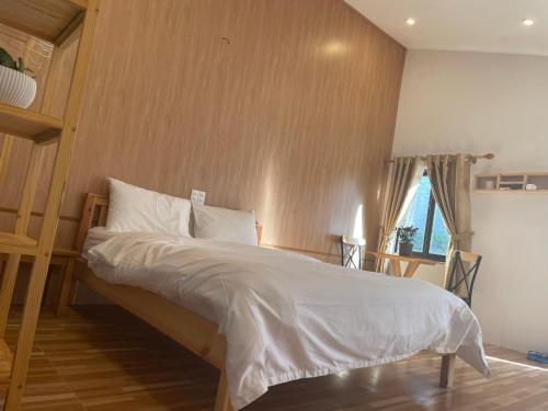 波来古市Pleiku Homestay的一间卧室配有一张带白色床单的床和一扇窗户。