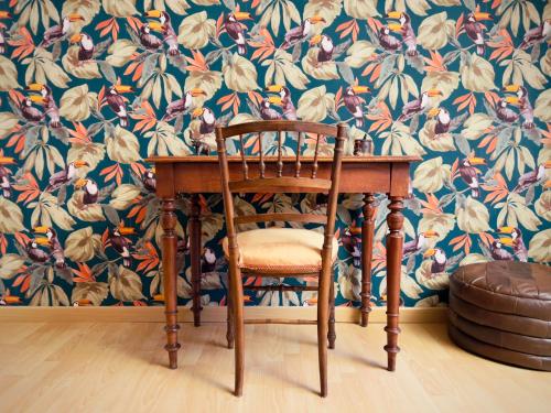 勒芒Chambre D'hôtes Francine et Gérard的一张木桌和一张带花卉壁纸的椅子