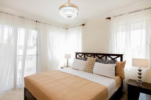 蓬塔卡纳The Ultimate Escape Unpack Relax Enjoy的卧室配有一张带白色窗帘的大床