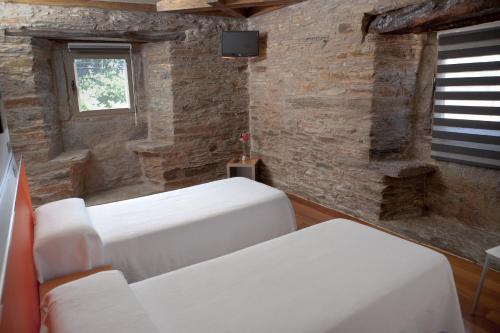 萨尔塞达艾伯格图里蒂科萨塞达酒店的石墙客房内的2张白色床