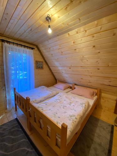 亚霍里纳Etno kuća ''Nada''的木制客房内的一张大床,设有窗户