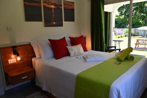 普拉兰大安塞区ANV HOLIDAY APARTMENTS的一间卧室配有一张带红色和绿色枕头的大床