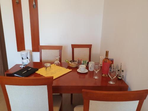 阳光海滩Apartment Ashton Hall - Sonnenstrand – Ost的桌椅和带酒杯的木桌