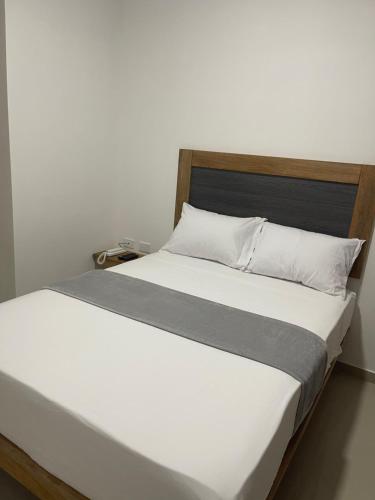 卡塔赫纳Hotel El Faro的白色的床、木制床头板和白色枕头