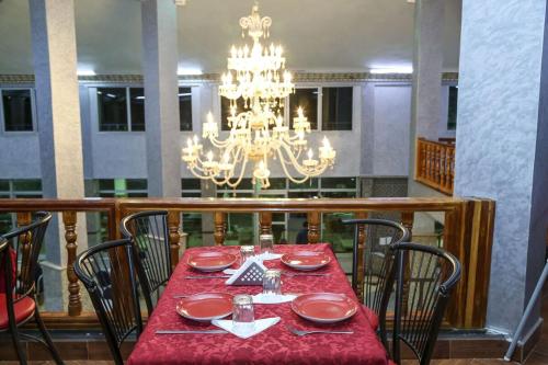 ZeïdaHOTEL LA POMME ZAIDA的一间带红色桌子和吊灯的用餐室
