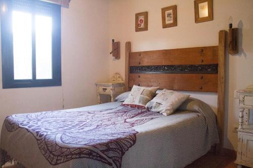 贝纳卢普-卡萨斯维耶哈斯CASA HUGANA的一间卧室配有一张大床和木制床头板