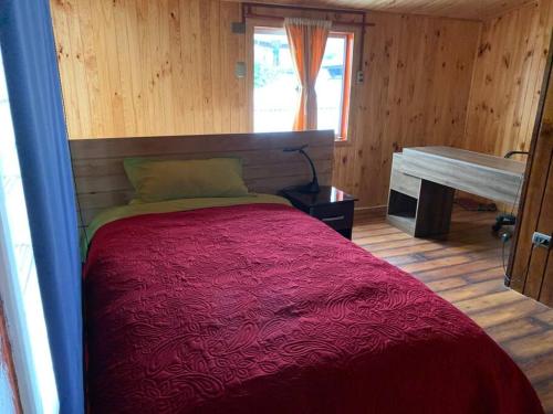 达卡卫Casa Centro Dalcahue的一间卧室配有一张带红色毯子的床